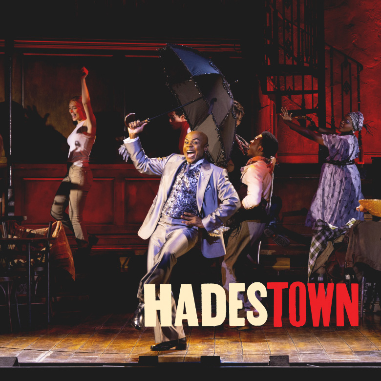 Hadestown cast on stage with logo